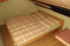 Una cama individual con una colcha escocesa y un cabecero de madera en una habitación con techo inclinado.