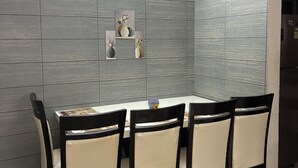 Zona pranzo con un tavolo rettangolare, sei sedie e pareti grigie dalla texture materica.