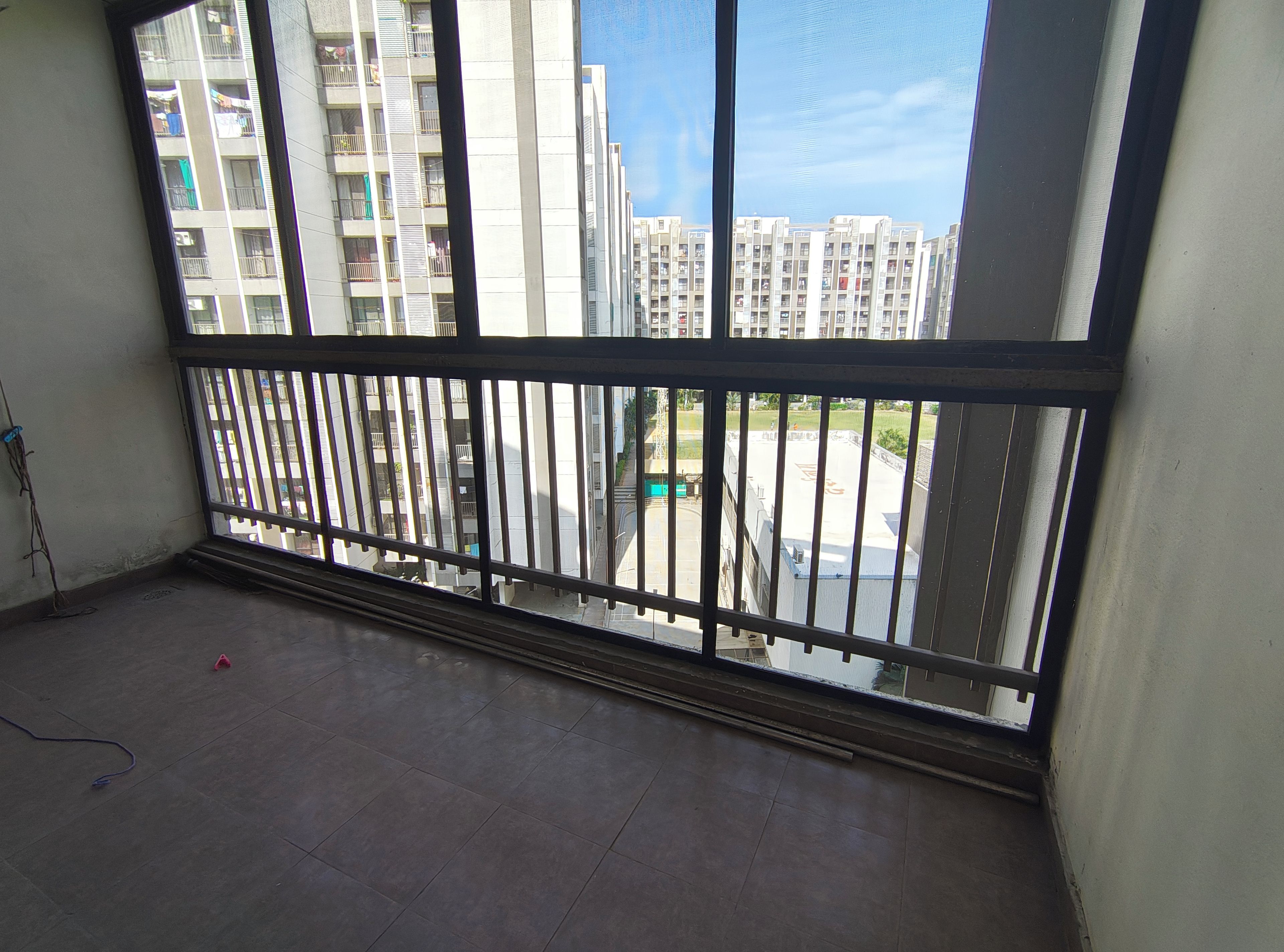 Un balcon doté d’une rambarde en métal, d’un sol carrelé et offrant une vue sur des immeubles de grande hauteur.