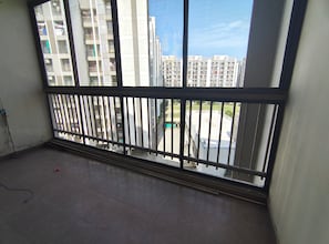 A balcony with a metal railing, a tiled floor, and a view of high-rise buildings.