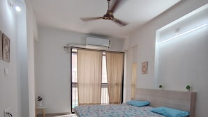 Una camera da letto con un letto, ventilatore a soffitto, condizionatore d'aria e vista attraverso una finestra con tende.