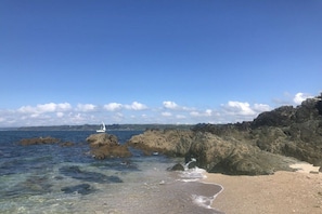 Un paisaje costero con aguas cristalinas, afloramientos rocosos y una playa de arena.