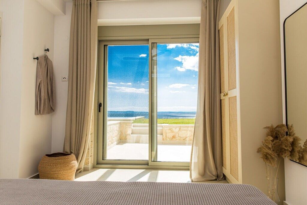 Ein Schlafzimmer mit Meerblick durch eine Schiebetür.