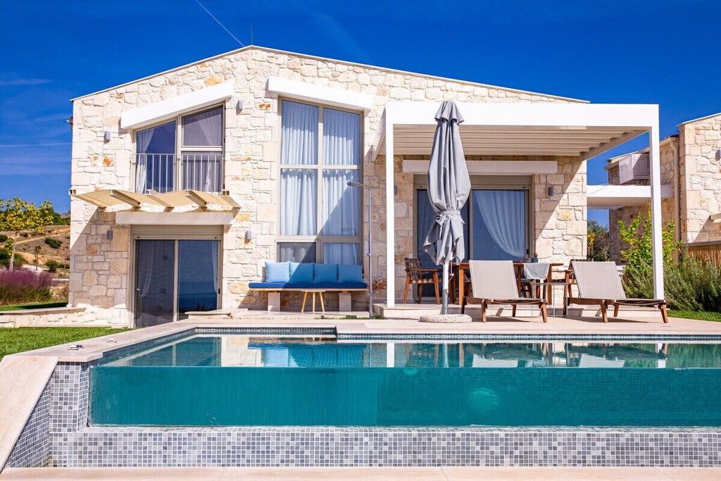 Ein zweistöckiges Steinhaus mit Pool, Außenbereich und überdachter Terrasse.