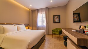 Habitació d'hotel amb un llit gran, un escriptori, una cadira i una televisió.