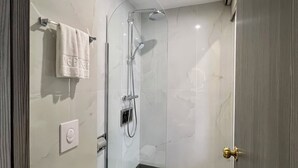 Un bany modern amb dutxa amb envidriament, vàter i paraigua per a tovallons.
