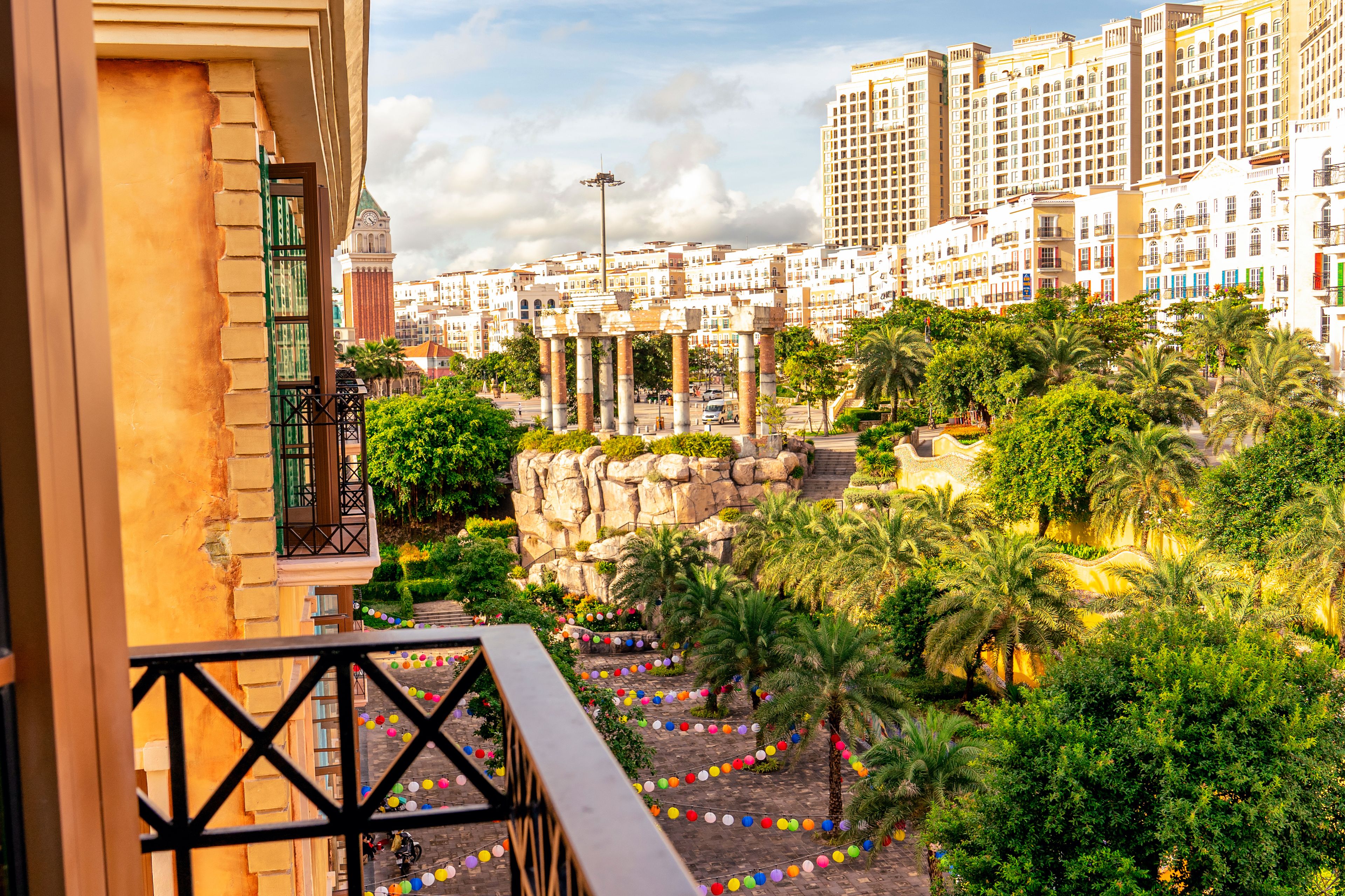 A balcony with a view of a cityscape, including a large building with columns and a clock tower.