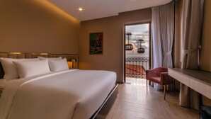 Habitació d'hotel amb un llit gran, una taula, una cadira i vista exterior.