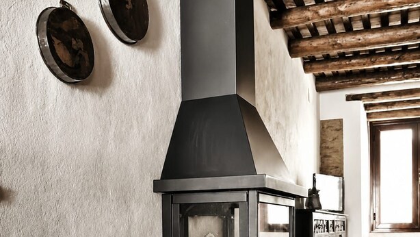 A stone-floored room with a fireplace, a woven basket of firewood, and a wooden ceiling. - Tu refugio rústico con encanto andalusí: descanso, historia y naturaleza. (Constantina)