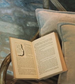 Ein offenes Buch auf einem Sessel mit Kissen.