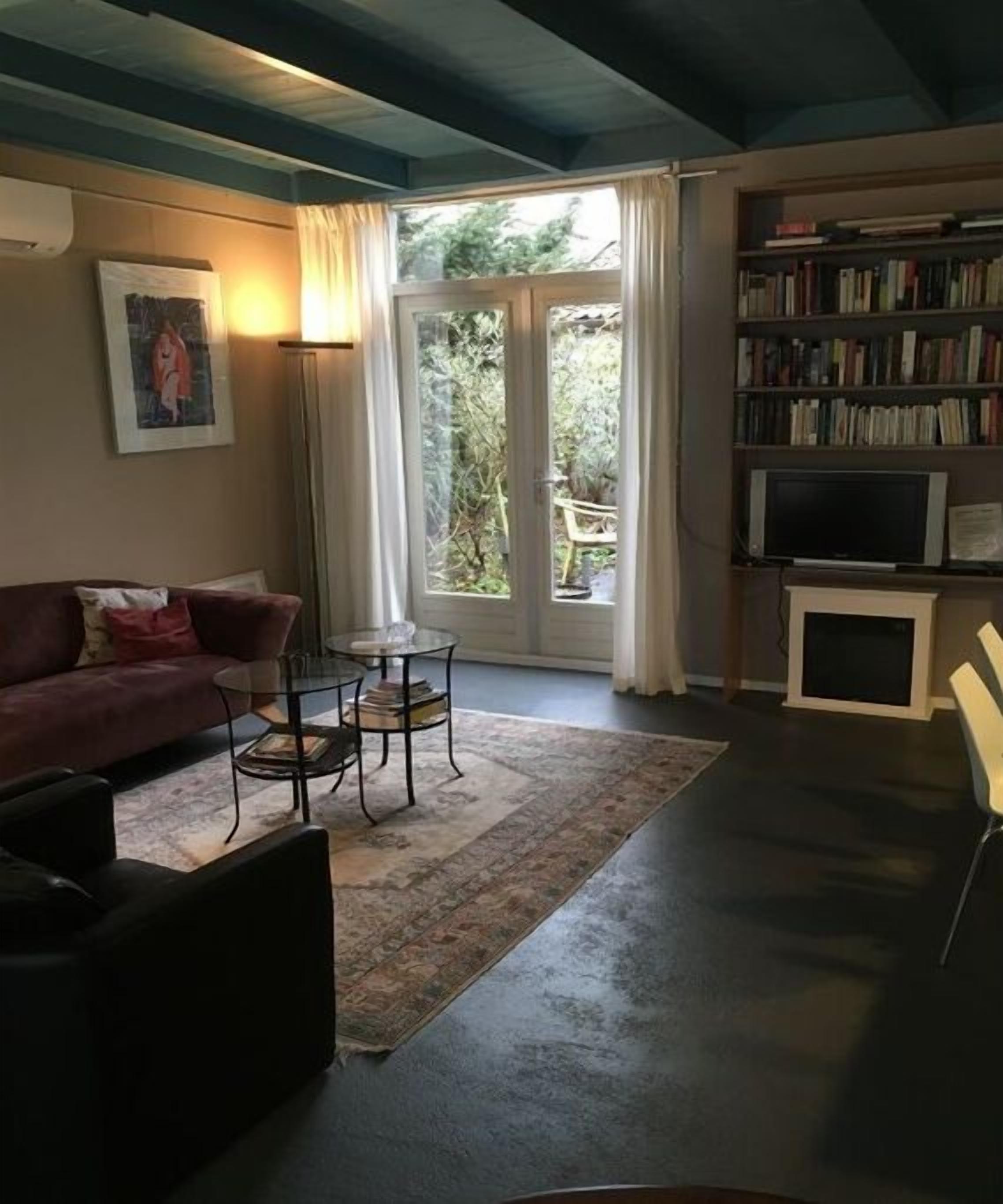 Een woonkamer met een bank, een salontafel, een boekenkast en een televisietoestel.