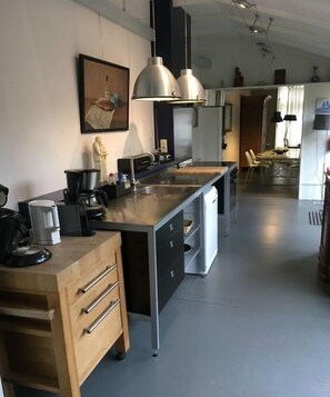 Een moderne keuken met een centraal eiland, roestvrijstalen apparatuur en hanglampen.