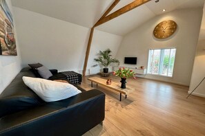 Un salon moderne avec un canapé en cuir noir, une table basse en bois et une grande fenêtre laissant entrer la lumière naturelle.