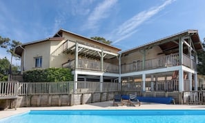 A two-story building with a swimming pool in the foreground. - Gallery Beach Villa Moliets, 15p (Moliets)