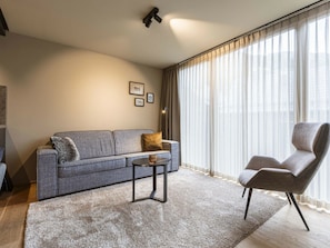 A modern living room with a grey sofa, a small coffee table, and a leather armchair. - Superior Penthouse With 2 Bedrooms (Schruns)