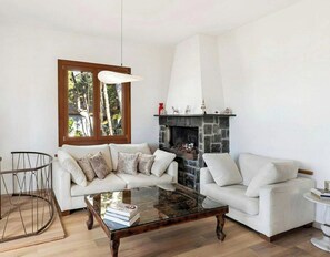 A living room with a fireplace, two sofas, a coffee table, and a dining table. - Hillside villa with terraced garden near Bajardo (Bajardo)