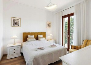 Een hotelkamer met een bed, nachtkastjes, lampen, een stoel en twee foto's in lijsten aan de muur.