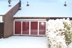 Ein Gebäude mit einem Metall-Dach, einem großen Fenster mit roten Vorhängen und einem mit Schnee bedeckten Untergrund.