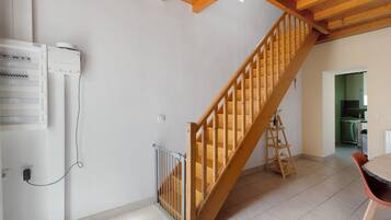 Un escalier avec des rampes en bois menant à l’étage supérieur, un coin cuisine équipé d’un lave-vaisselle et une table à manger avec des chaises.