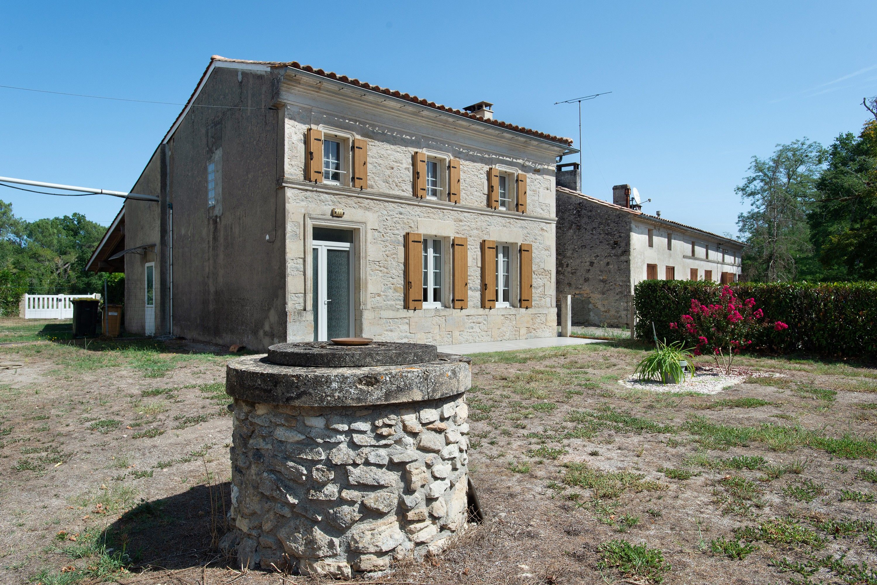 A two-story stone building with a flat roof and wooden shutters.