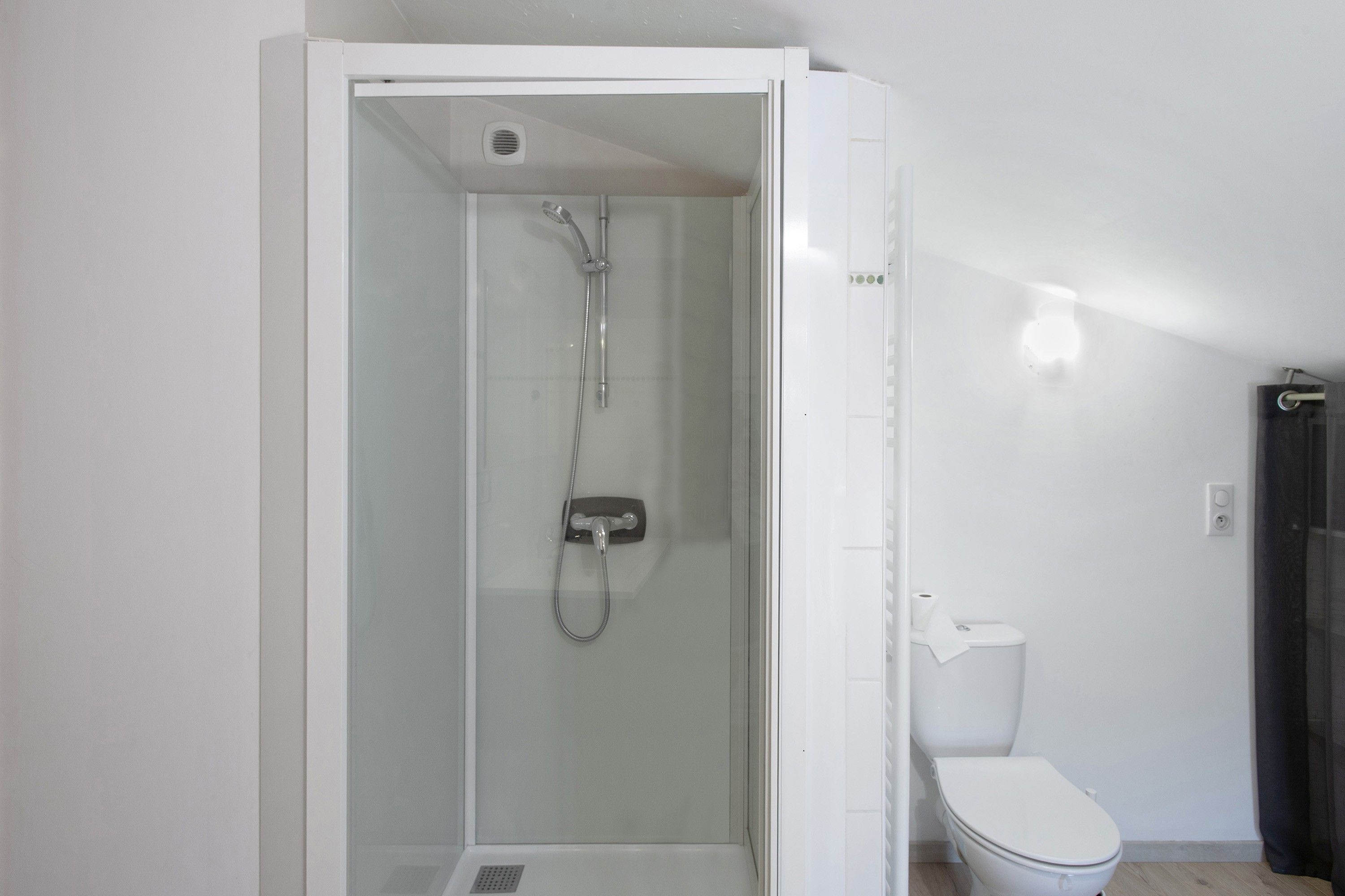 Une salle de bain avec une douche à parois de verre, des toilettes et un rideau de douche.