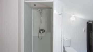 Une salle de bain avec une douche à parois de verre, des toilettes et un rideau de douche.