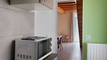 Una cucina con un forno a microonde sul bancone, una finestra e un'area pranzo con una sedia e un tavolo.