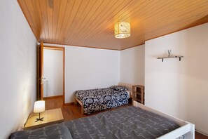 Una camera da letto con un letto, un comodino, una lampada e una mensola con una sveglia.
