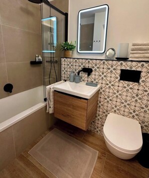 A bathroom with a bathtub, a sink, a toilet, and a shower area. - Apartment 182, Sea Love (Juist)