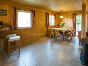 Interior de madeira com área de jantar, cadeiras, mesa e fogão.