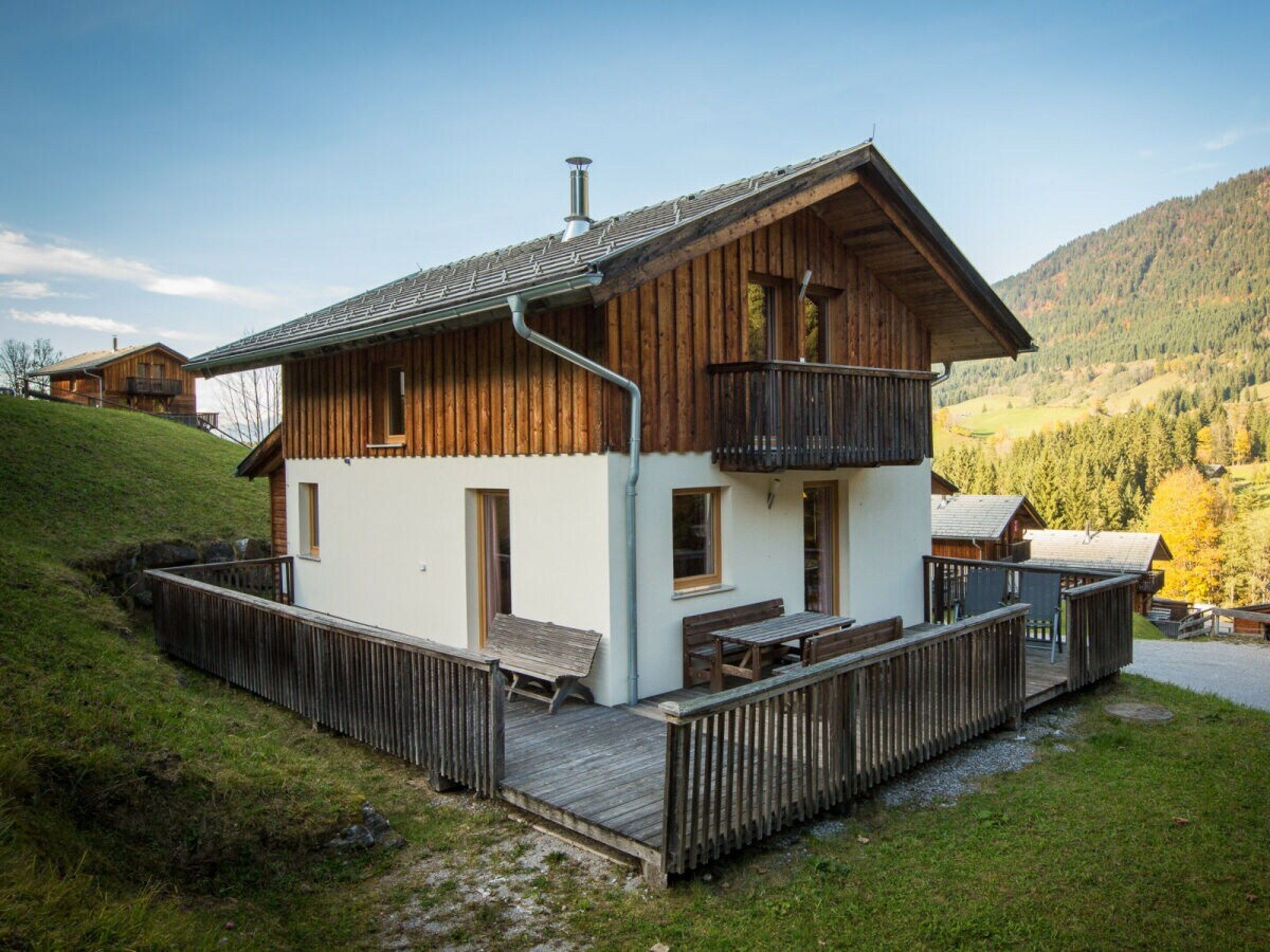 A chalet with a wooden exterior, a balcony, and a deck area.