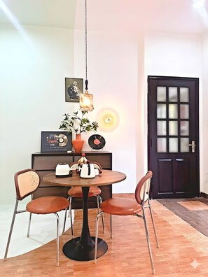 Ein Essbereich mit einem runden Tisch, vier Stühlen, einer Hängelampe, einem Blumentopf und einer Tür mit satinierten Glasfeldern.