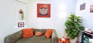 A living room with a sofa, a large green plant, and a framed picture on the wall. - Nary Home Private1BR near My Khe BeachI Sleeps 4 I Kitchen l Washer Dryer l 2 AC (Đà Nẵng)