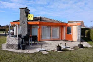 A modern house with a patio, a chimney, and a smiley face decoration. - Bungalow with 1 bedroom (Julianadorp aan Zee, Niederlande, Europa)