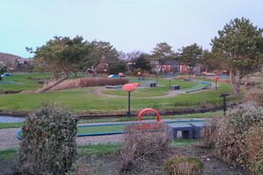 Ein Park mit einer grünen Wiese, Bäumen und einem roten, kreisförmigen Objekt.