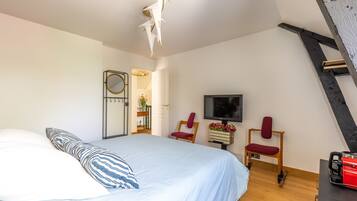 A bedroom with a bed, a TV, a chair, and a desk.