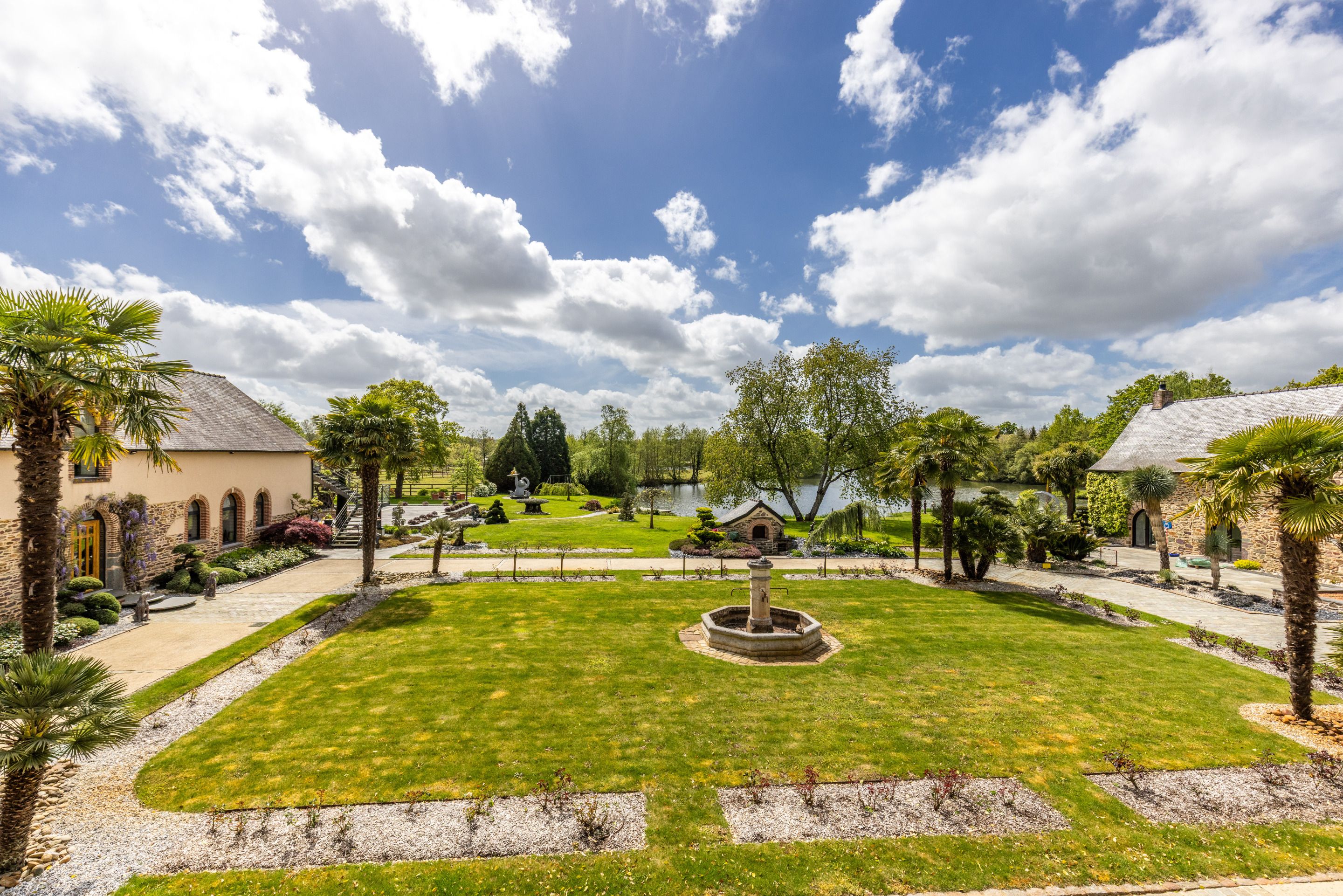 Un jardín ajardinado con una fuente central, senderos y una variedad de árboles y arbustos.