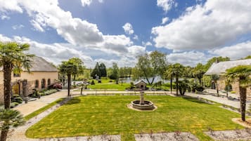 Un jardin aménagé avec une fontaine centrale, des allées et une variété d’arbres et d’arbustes.