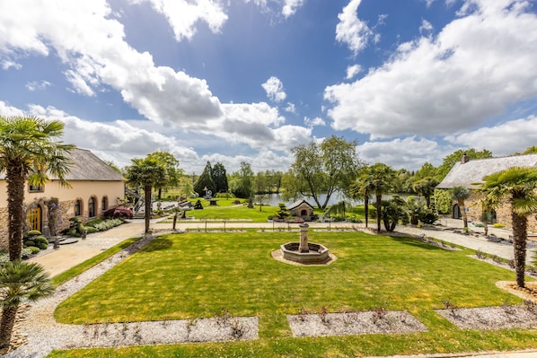 Un jardín ajardinado con una fuente central, senderos y una variedad de árboles y arbustos.