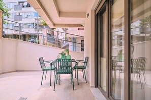 Ein Balkon mit Tisch und Stühlen, einem Blumentopf und Blick auf angrenzende Gebäude.