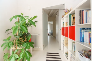 A hallway with a radiator, a plant, and a bookshelf with books and a red storage unit. - Room 'A Casa Di Giò Per Un Totale Relax' with Private Terrace, Wi-Fi and Air Conditioning (Guarrato)