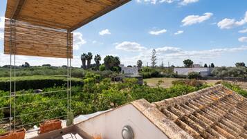 A rooftop terrace with a view of a landscaped garden, a wooden pergola, and a clear blue sky.