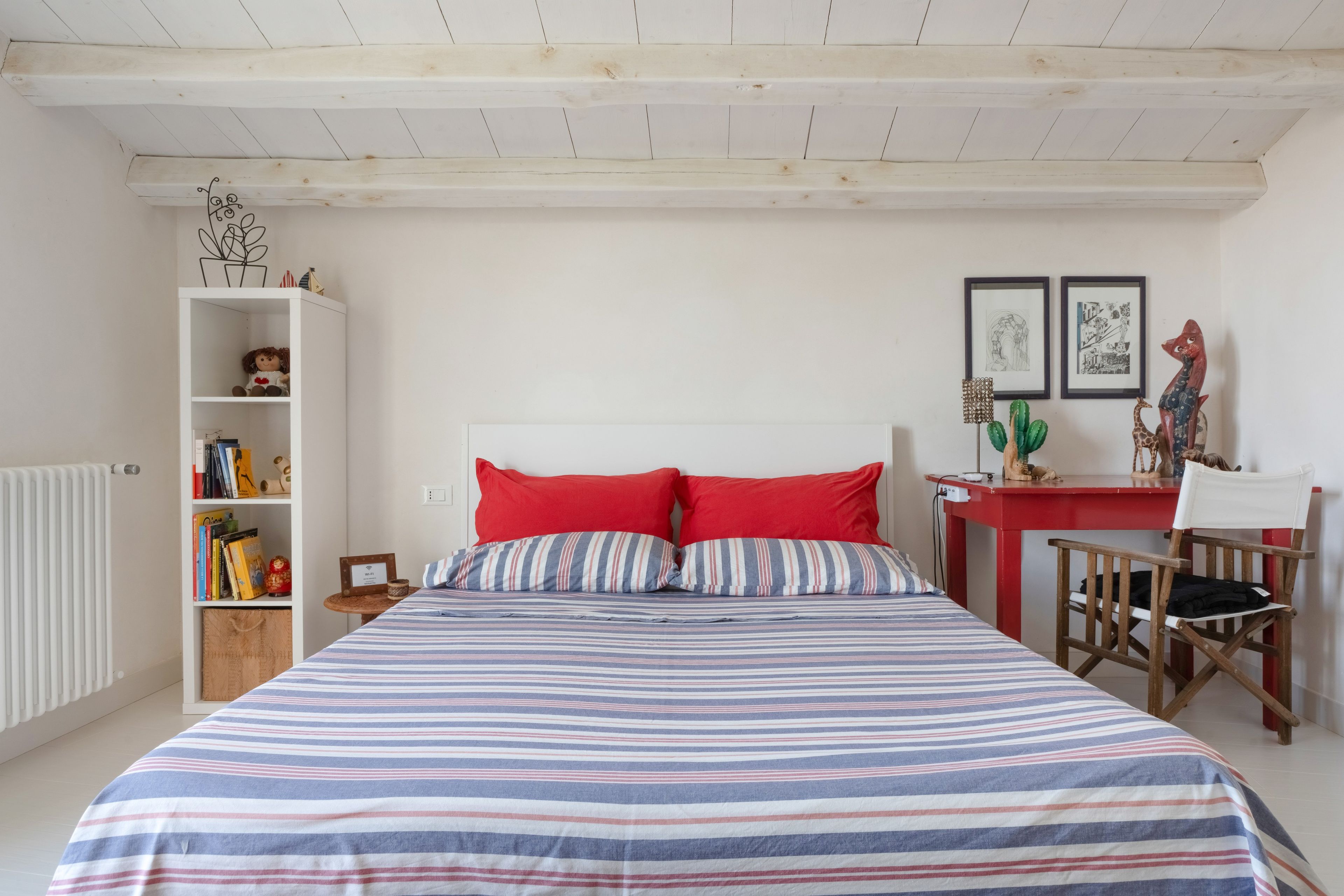 A bedroom with a bed, a desk, a chair, a bookshelf, and a radiator.