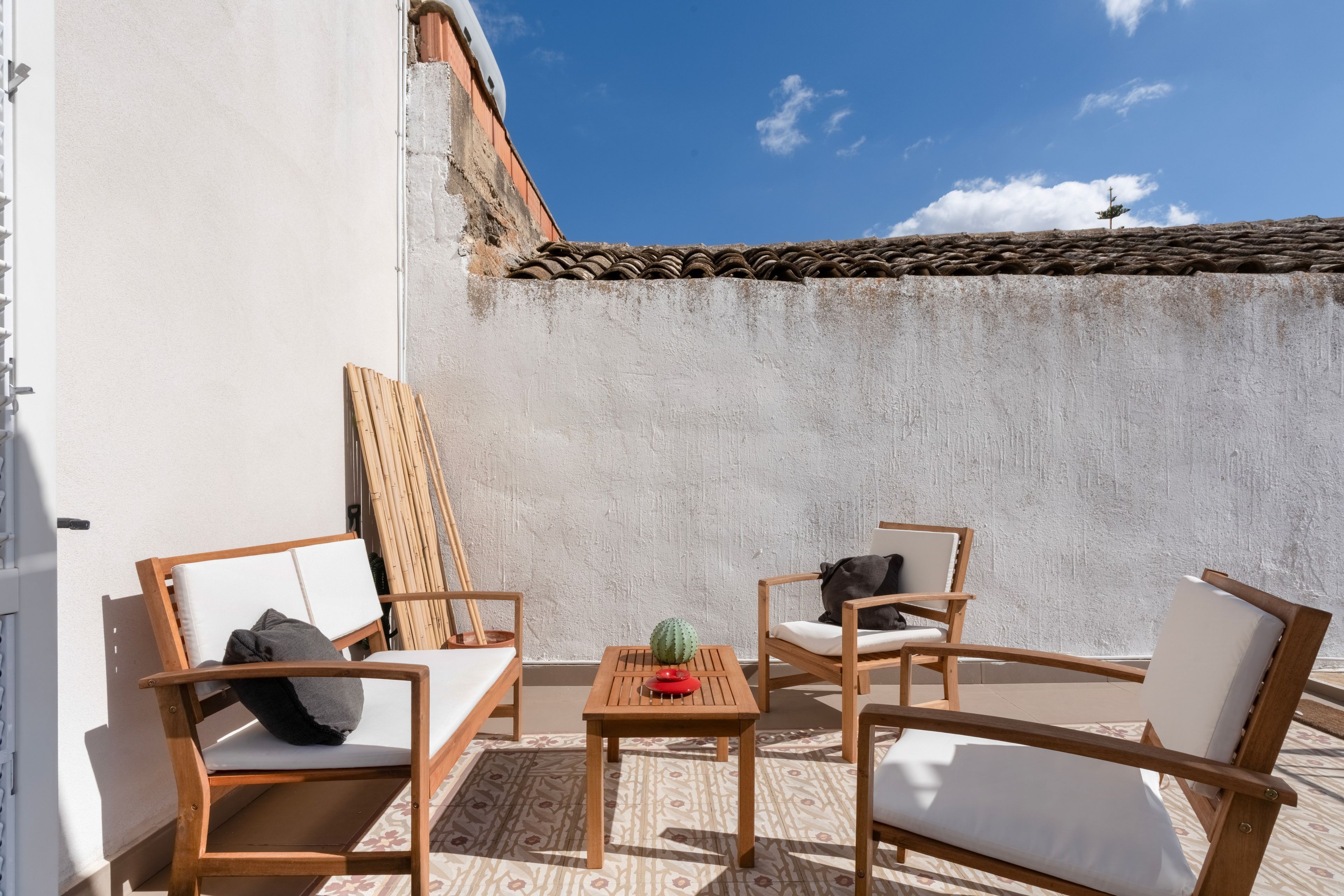 Eine Terrasse mit Holzmöbeln, einem kleinen Tisch und einer Kakteendekoration.