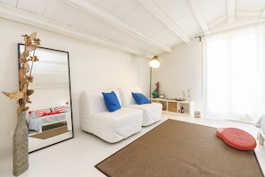 A modern living room with a white sofa, a large mirror, and a decorative plant. - Room 'A Casa Di Giò Per Un Totale Relax' with Private Terrace, Wi-Fi and Air Conditioning (Guarrato)