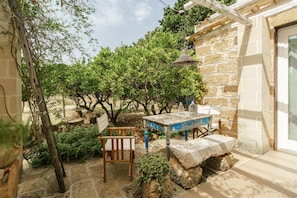 A rustic outdoor seating area with a stone table and chairs, surrounded by greenery and a stone wall. - Room 'A Casa Di Giò Per Un Totale Relax' with Private Terrace, Wi-Fi and Air Conditioning (Guarrato)
