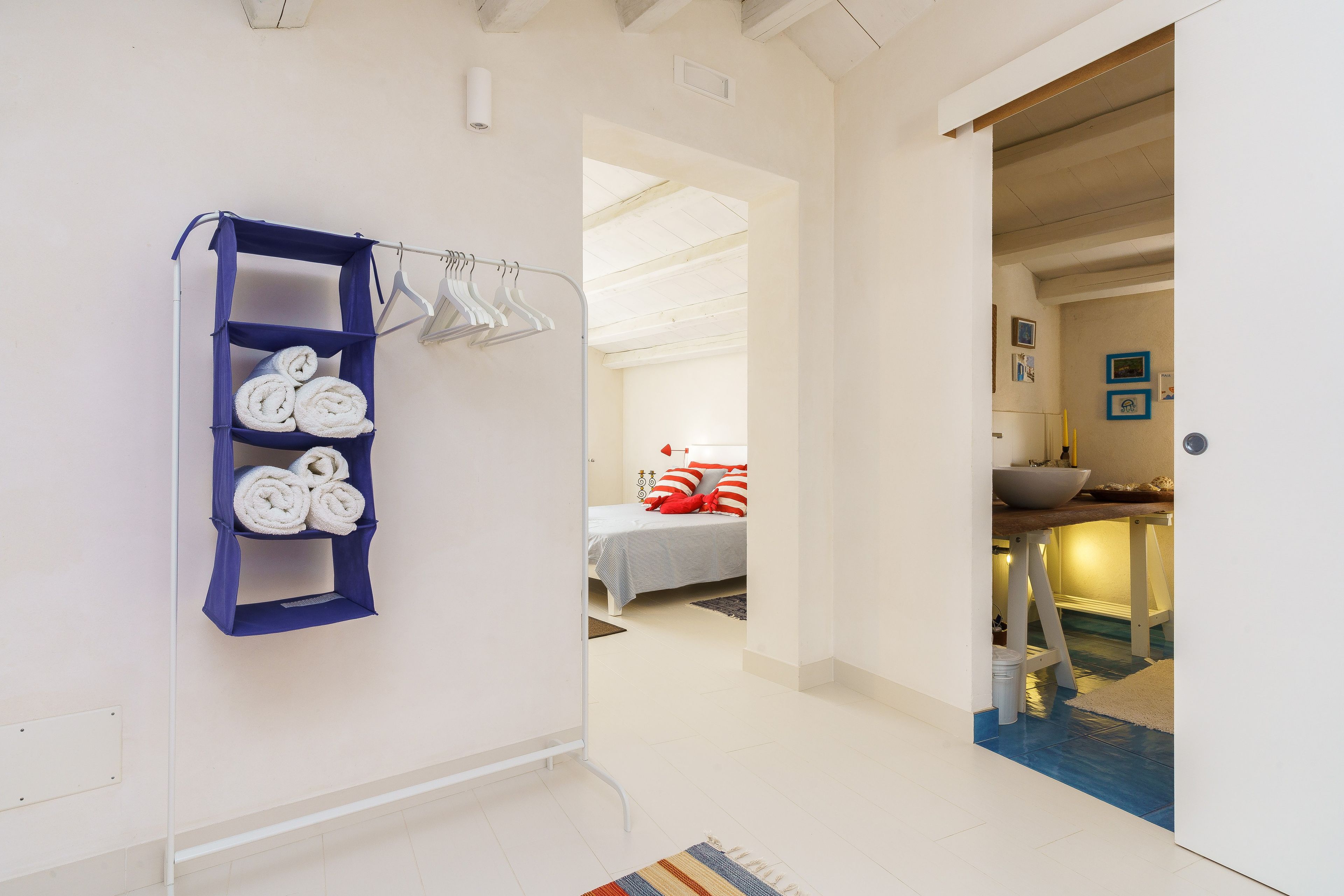 Une chambre d’hôtel avec un lit, une salle de bain avec un lavabo et un couloir avec un porte-serviettes.