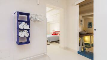 Une chambre d’hôtel avec un lit, une salle de bain avec un lavabo et un couloir avec un porte-serviettes.