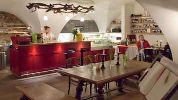 A restaurant interior with a red bar counter, wooden tables, and chairs.
