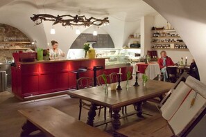 A restaurant interior with a red bar counter, wooden tables, and chairs. - 3 Weingut Hauerhof 99 (Klosterneuburg)